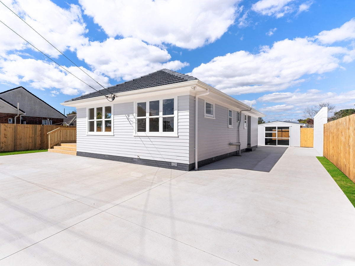 Renovated house with a new concrete driveway running to the rear of the section